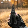 Mano con guante táctico sosteniendo una multiherramienta negra HX Outdoors en un campo otoñal