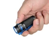 Linterna Olight Baton 4 negra con detalles azules sostenida en mano, con patrón de agarre, ideal para uso diario.