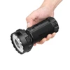 Mano sosteniendo una linterna potente Olight Marauder 3 negra con lente LED grande sobre fondo blanco