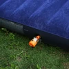 Mini bomba de aire eléctrica naranja inflando un colchón inflable azul sobre el césped