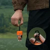 Persona sosteniendo mini linterna de camping naranja Flextail con mosquetón integrado al aire libre