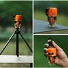 Linterna de camping naranja Flextail sobre trípode, mesa y sostenida con la mano al aire libre